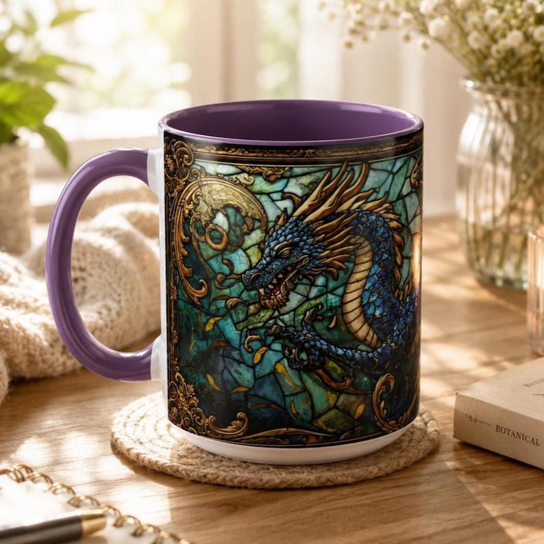 May include: A ceramic mug with a purple handle and interior, featuring a wrap-around design of a blue dragon set against a green and teal stained glass background with intricate gold filigree borders and decorative scrollwork elements.