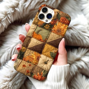 May include: A fall-themed phone case featuring a patchwork design with pumpkins, mums, and fall foliage in shades of brown, orange, and yellow. The case has a quilted appearance and a camera cutout.