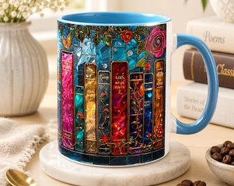 May include: A ceramic mug with a light blue interior and handle, featuring a vibrant stained-glass style graphic of colorful book spines, roses, and a butterfly. The design wraps around the exterior, showcasing various hues of red, gold, and blue.
