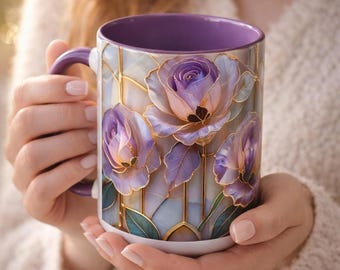 Può includere: Una tazza in ceramica bianca con interno e manico viola. L'esterno presenta un disegno di rose viola con contorni dorati e foglie verdi. La tazza è tenuta con entrambe le mani.