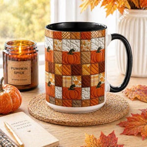 May include: A ceramic mug featuring a quilted patchwork pattern of orange pumpkins, autumn leaves, and plaid squares in shades of brown, orange, and cream. The mug has a solid black interior and a black handle, with a smooth, cylindrical shape.