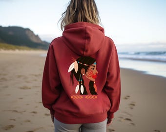 May include: A maroon hoodie with a Native American graphic on the back. The graphic features a profile of a woman with feathers, beads, and face paint. The hoodie has a hood and is worn with gray shorts on a beach.