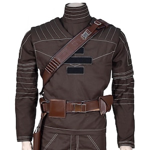 May include: Brown costume with a high collar, shoulder strap, and belt. The costume has white stitching details and black patches on the chest. A brown leather holster and pouch are attached to the belt.