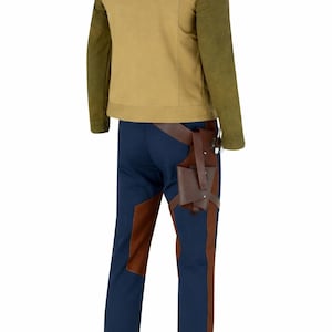 K&ouml;nnte beinhalten: Ein Kost&uuml;mset mit einer beigefarbenen Jacke mit olivgr&uuml;nen &Auml;rmeln, einer marineblauen Hose mit braunen Aufn&auml;hern und einem braunen Holster. Die Jacke hat einen Stehkragen. Die Hose hat eine schmale Passform. Das Holster ist an einem braunen G&uuml;rtel befestigt.