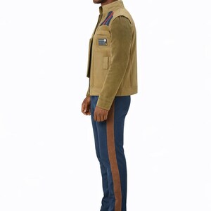 K&ouml;nnte beinhalten: Beige Jacke mit hohem Kragen und kleiner Tasche auf der Brust. Die Jacke hat einen dunkelgr&uuml;nen &Auml;rmel und wird mit einer blauen Hose mit braunem Streifen an der Seite kombiniert. Die Person tr&auml;gt braune Schuhe.