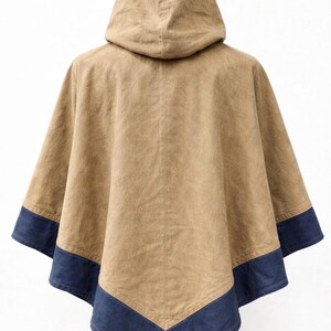 May include: A tan hooded poncho with a dark blue trim along the bottom edge. The poncho is made of a textured fabric and has a simple, classic design. The hood is attached to the back of the poncho.