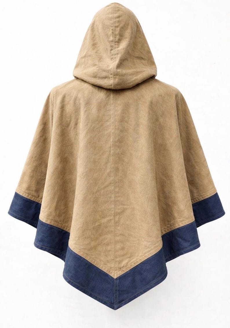 May include: A tan hooded poncho with a dark blue trim along the bottom edge. The poncho is made of a textured fabric and has a simple, classic design. The hood is attached to the back of the poncho.