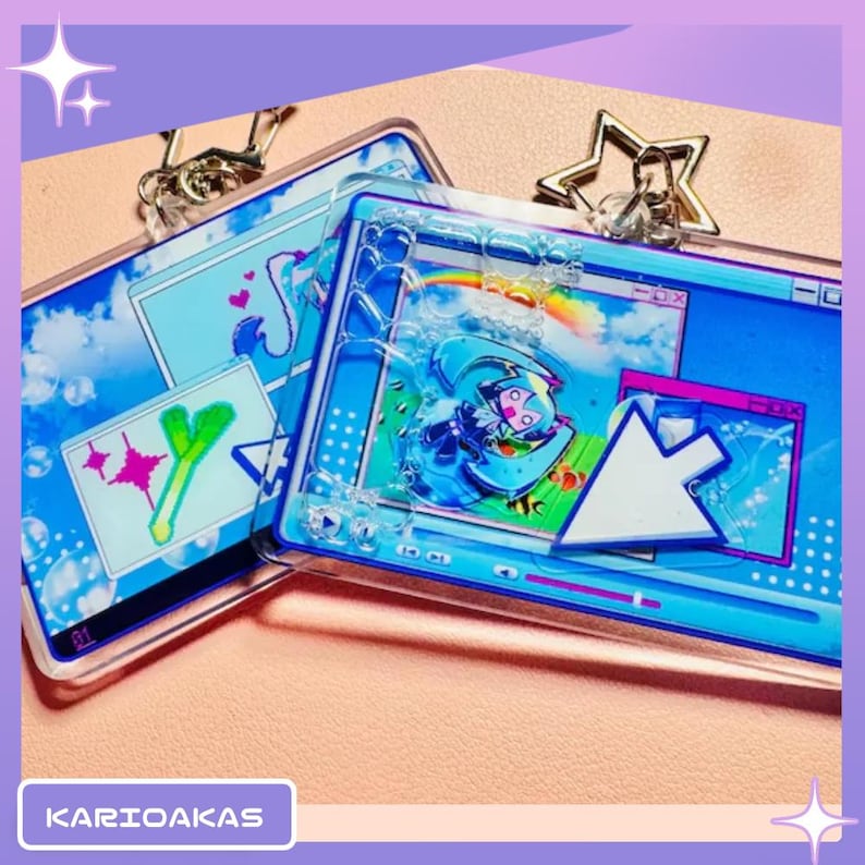 May include: Two rectangular acrylic keychains featuring a blue computer desktop interface design. The keychains include a floating cursor, a character graphic, and a rainbow. One keychain has a star-shaped metal clasp, and the text KARIOAKAS is visible.