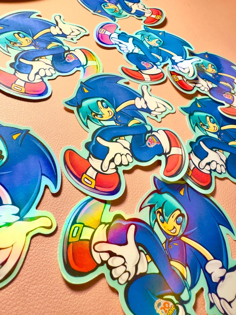 May include: Multiple die-cut stickers featuring a stylized anime-inspired character wearing a blue hooded jacket with spiky hair, white gloves, and red shoes with gold buckles. Each sticker displays a small circular logo with the text 20th Anniversary.