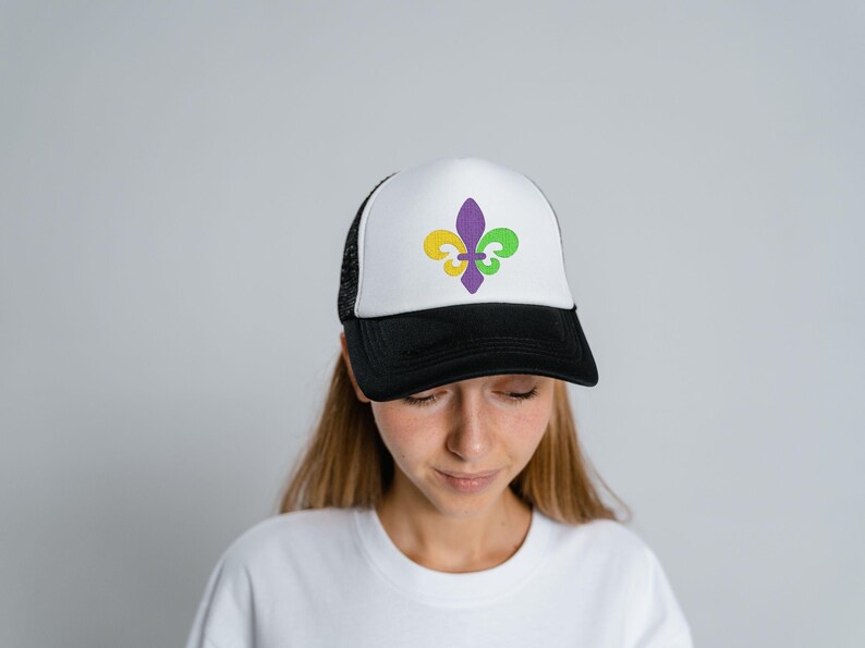Puede incluir: Una gorra de camionero blanca y negra con un dise&ntilde;o de flor de lis morado, amarillo y verde en la parte delantera.