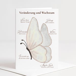Könnte beinhalten: Eine weiße Keramik-Tasse mit schwarzem Henkel und dem Text "But First, Coffee" in schwarzer, handschriftlicher Schrift. Die Tasse steht auf einer weißen Oberfläche.