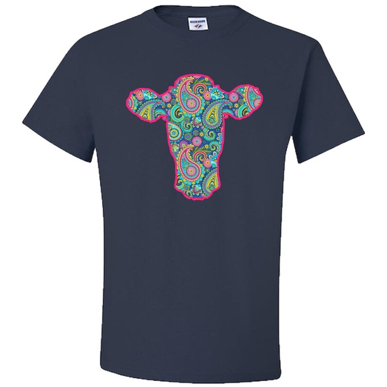 May include: A navy blue t-shirt featuring a pink outline of a cow's head filled with a paisley pattern in shades of blue, green, pink, and yellow.