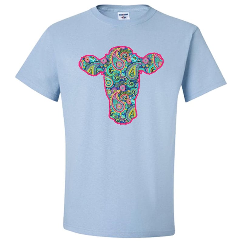 May include: Light blue t-shirt featuring a pink outline of a cow's head filled with a paisley pattern in shades of blue, green, pink, and yellow.