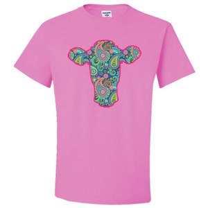 May include: Pink t-shirt featuring a cow's head design with a paisley pattern.