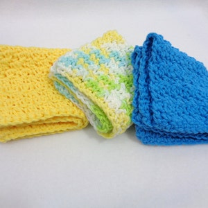 May include: Three crocheted dishcloths in yellow, green and white, and blue.