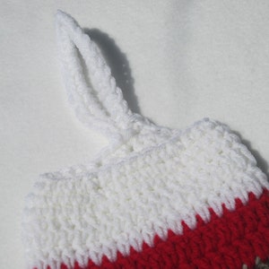 May include: White, red, and brown crocheted stocking with a white loop handle.