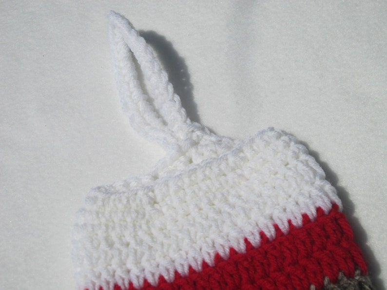 May include: White, red, and brown crocheted stocking with a white loop handle.