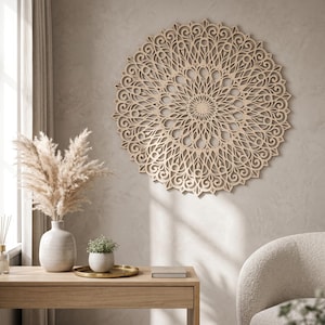May include: A large, intricately carved wooden mandala wall art piece. The circular design features a detailed pattern of swirling lines and floral elements. The natural wood colour complements the neutral-toned wall, creating a focal point in the room.