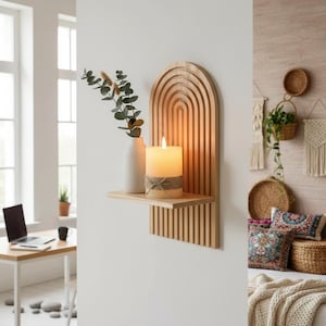 Puede incluir: Estante de pared de madera con diseño arqueado, con una vela encendida, un jarrón blanco con vegetación y un pequeño estante. El estante es de madera clara y tiene una estética minimalista.
