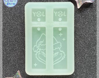 May include: A green silicone mold for making earrings. The mold has two sections, each with a Grinch design and the text "YOL" on top.