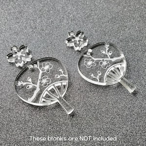 May include: Four clear acrylic earrings with a floral design. The earrings are shaped like fans and feature a delicate floral pattern.