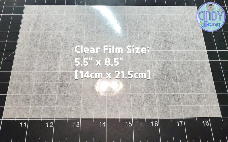 May include: A clear film sheet on a black grid surface. The film is 5.5 inches by 8.5 inches, or 14 centimeters by 21.5 centimeters.