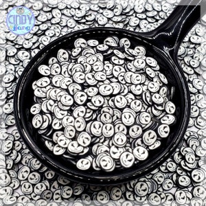 May include: A black bowl filled with white and black Halloween-themed sprinkles. The sprinkles are shaped like Jack Skellington's face from the movie The Nightmare Before Christmas.