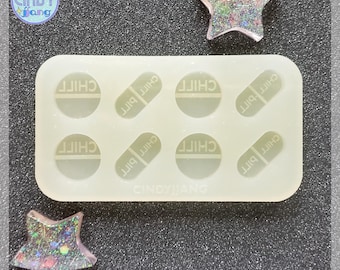 May include: A white silicone mold with eight cavities for making resin pill charms. The mold has a rectangular shape and features the text "CHILL PILL" in each cavity.