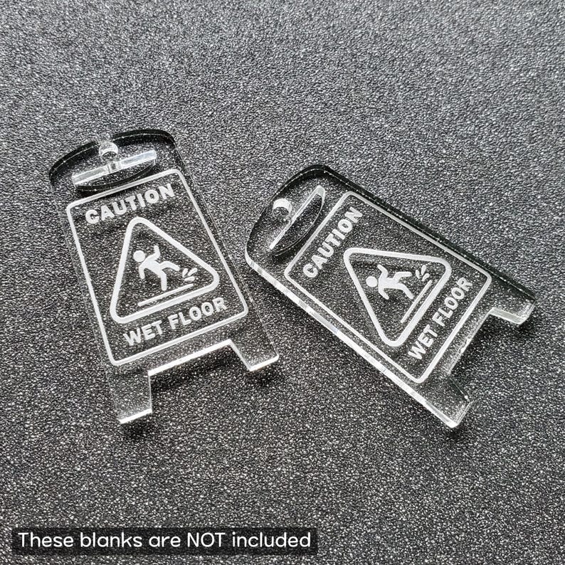 May include: Two clear acrylic caution signs with the text "Caution Wet Floor" and a stick figure slipping on a wet surface.