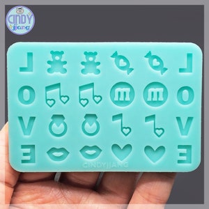 May include: A turquoise silicone mold with various shapes including letters, musical notes, hearts, bears, candy, rings, and lips. The mold is labeled "CINDYJIANG" at the bottom.