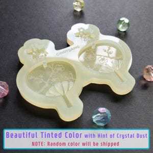 May include: A clear silicone mold with three impressions of a Japanese fan with cherry blossoms. The mold is translucent and has a slight sparkle. The text "CINDYJJANG" is visible on the mold.