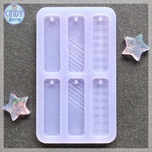 May include: A clear silicone mold with six rectangular cavities for making resin crafts. The mold has a textured design in each cavity, including a plain, striped, and plaid pattern. The mold is labeled "CINDYJIANG".