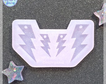 May include: A white silicone mold for making earrings. The mold features three lightning bolt shapes, two smaller ones and one larger one. The mold is labeled "CINDYJIANG".