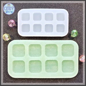 May include: Two silicone molds for making square resin crafts. The top mold is white and the bottom mold is light green.