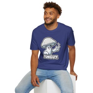 May include: A royal blue t-shirt with a cartoon mushroom graphic and the text "FUNGUY." The mushroom is white and has a smiling face with one arm raised and pointing to the right.