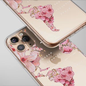 Może przedstawiać: Przezroczyste etui na telefon z kwiatowym wzorem mapy świata. Różowy kwiatowy wzór jest nałożony na mapę świata, z widocznym tekstem Oceanu Południowoatlantyckiego. Etui mają przezroczową obwódkę i złotą ramkę.