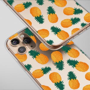 May include: Two clear phone cases featuring a repeating pattern of orange pineapples with green tops. The cases are angled, revealing the camera lenses and edges. The background is a light grey.