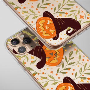 Può includere: Due custodie trasparenti per telefono con un design a tema Halloween. Le custodie presentano un motivo ripetuto di zucche arancioni con cappelli da strega marroni, circondate da foglie verdi, punti e stelle arancioni. Le custodie sono angolate.