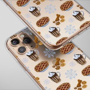 May include: Clear phone case with a repeating pattern of pie, hot chocolate, snowflakes, cinnamon sticks, and orange slices. The case is designed to fit a smartphone, with a clear border and a gold-colored camera ring.