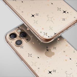 Könnte beinhalten: Zwei transparente Handyhüllen mit goldfarbenem Rahmen und einem Muster aus schwarzen, goldenen und rosa Sternen. Die Handyhüllen befinden sich auf einem hellgrauen Hintergrund. Die Handyhüllen überlappen sich leicht.