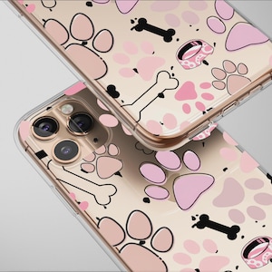 May include: Two clear phone cases with a pink paw print, bone, and dog bowl pattern. The cases have a gold-colored border and are set against a light background. The design is repeated on both cases.