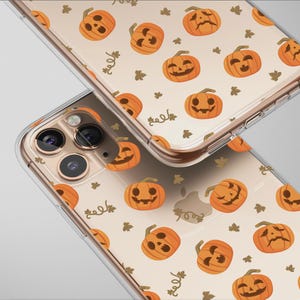 Könnte beinhalten: Zwei transparente Handyhüllen mit einem sich wiederholenden Muster aus orangefarbenen Kürbissen und grünen Blättern. Die Handyhüllen befinden sich auf einem hellen Hintergrund. Die Handyhüllen haben ein klares, schützendes Design.