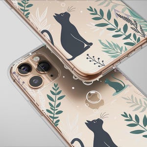 May include: Clear phone cases with a cat and botanical design. The cases feature a repeating pattern of black cats, green leaves, and white floral elements. The cases are shown stacked, with the camera lenses visible.