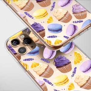 May include: Clear phone case featuring a repeating pattern of cupcakes, macarons, lemon slices, and lavender sprigs. The cupcakes have purple and cream frosting. The macarons are yellow, purple, and blue. The case is designed for a smartphone.