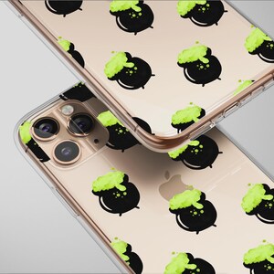 May include: Two clear phone cases with a repeating pattern of black cauldrons with green bubbling potion. The cases are on a light gray background. The phone cases have a gold-colored frame.