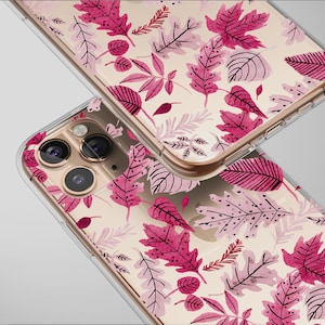 May include: Two clear phone cases with a repeating pattern of pink and light pink leaves on a cream background. The cases have a gold-colored frame and are angled towards the viewer.