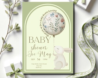 May include: A baby shower invitation with a light green background. The invitation features a balloon with floral designs held by a white bunny. The text reads "BABY shower Joe May" with the date and time. Additional text includes "Please join us for a baby shower honoring".