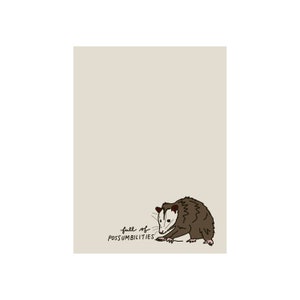 Peut inclure: Impression beige avec un opossum de dessin animé avec une fourrure brune, un visage blanc et le texte "full of possumibilities". L'opossum est dessiné dans un style fantaisiste, avec une expression enjouée.
