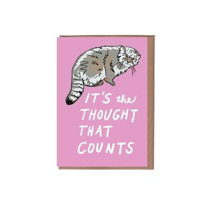 Puede incluir: Una tarjeta de felicitación con un fondo rosa y una ilustración de dibujos animados de un gato. El gato es gris y blanco con marcas negras. El texto "IT'S the THOUGHT THAT COUNTS" está escrito en blanco.