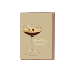 May include: A greeting card with a brown background and a drawing of a cocktail glass with a brown liquid and a light brown top. The text "Something Special" is written in white cursive on the card.